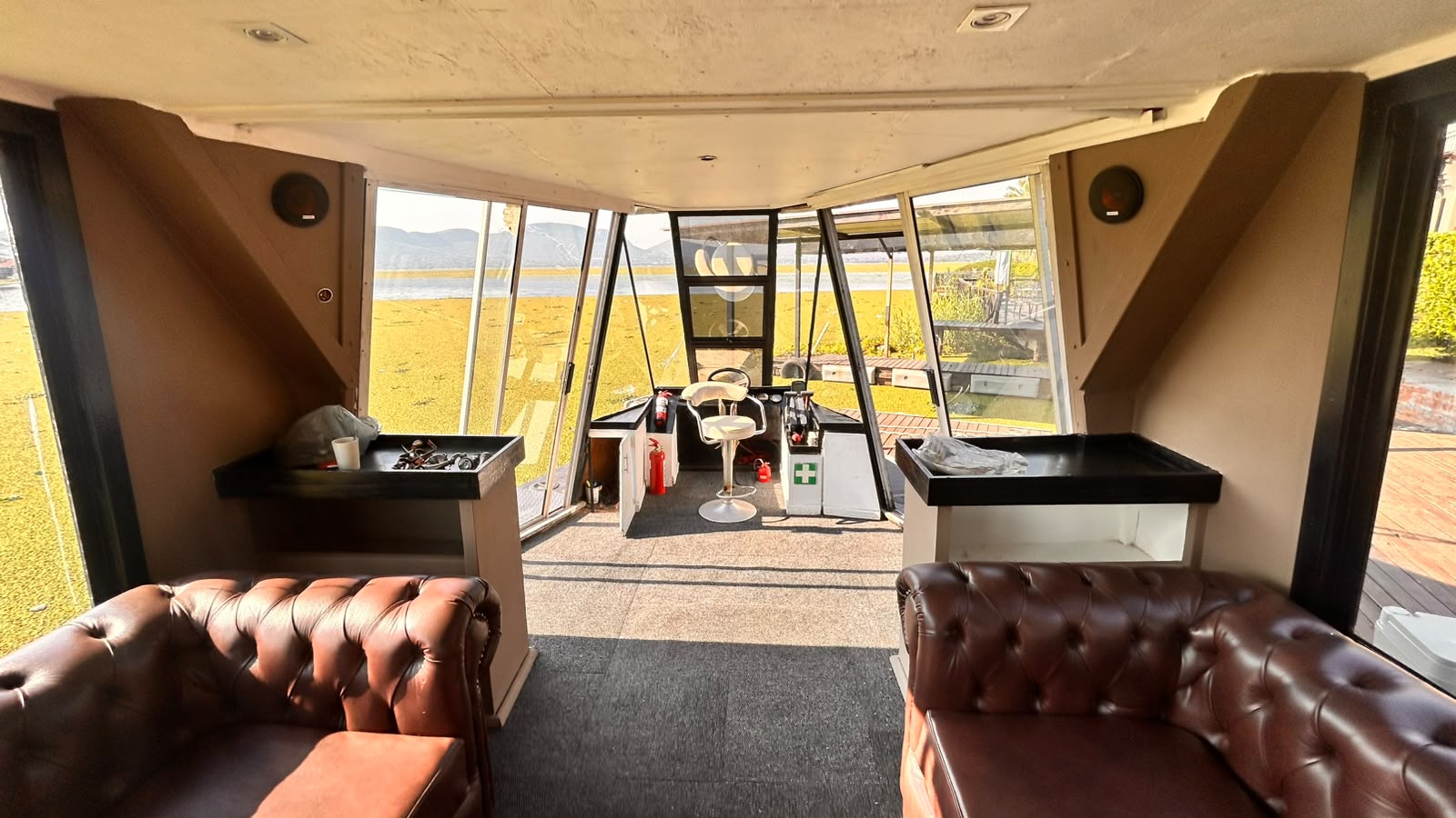 The cabin, with facing runs of buttoned leather and the dam through the windows